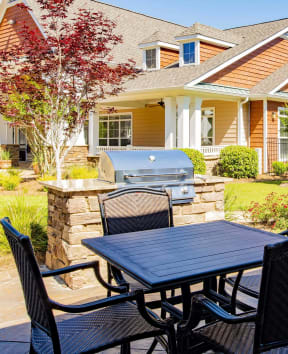 a patio with a table and chairs and two bbq grills in front of a