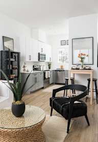 A modern kitchen with a black chair and a glass table.