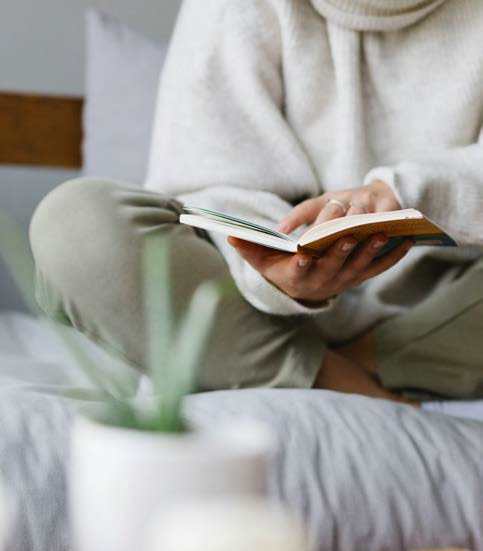 A person is reading a book on a bed.