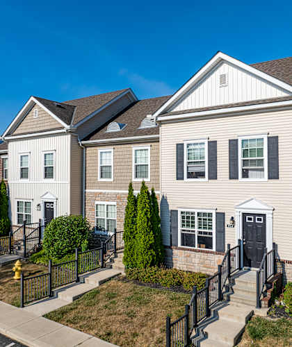 A two-story house with a white and grey exterior and a black fence.