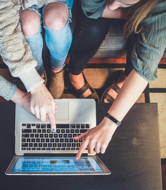 a group of people sitting around a laptop computer
