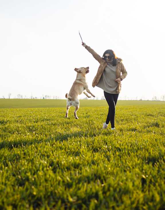 A woman is playing with her dog in a field.