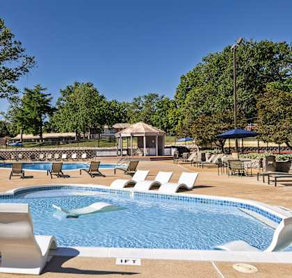 A pool with chairs around it and a building in the background.