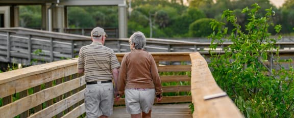 an older couple walking down a wooden bridge