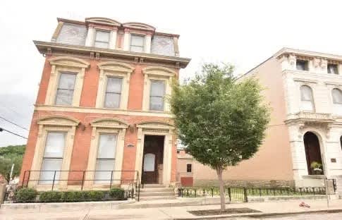 A red brick building with a tree in front.