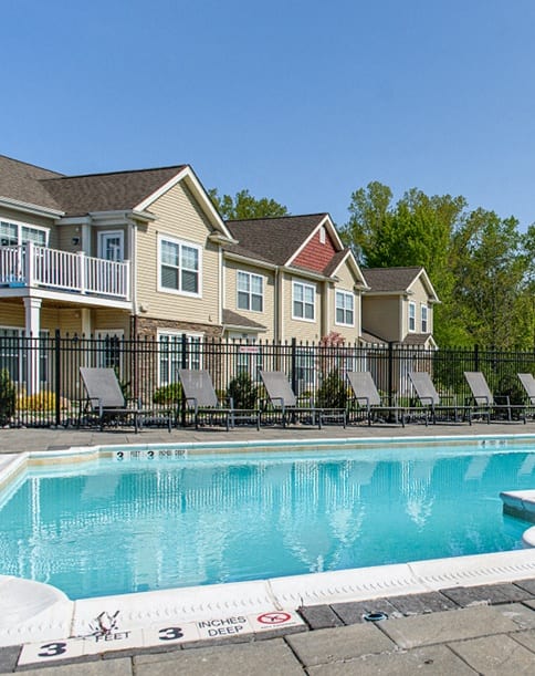 our resort style swimming pool is surrounded by chairs and a white fence