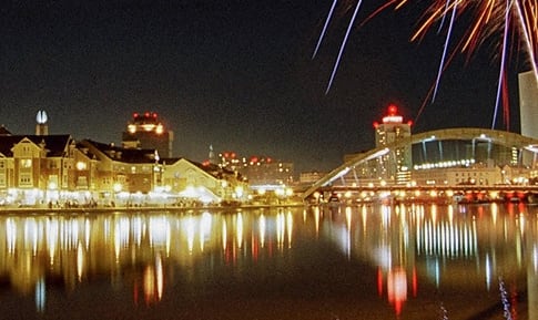 View of Corn Hill Landing exterior at night from across the river during a fireworks celebration