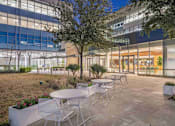 Thumbnail 3 of 24 - A patio with tables and chairs is set up outside a building.
