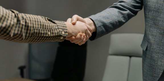 Two people shaking hands in an office setting.