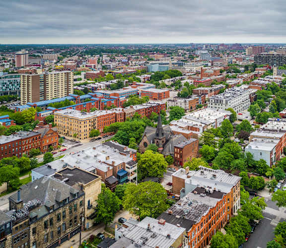 A cityscape with buildings and trees under a cloudy sky.