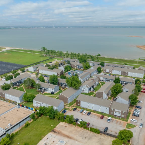 an aerial view of a row of houses with a body of water in the background