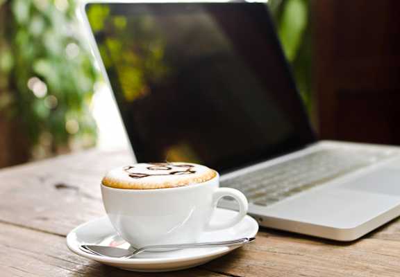 a cup of coffee sitting next to a laptop computer