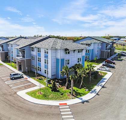 A parking lot in front of a row of blue and white buildings.