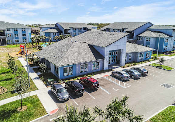 A parking lot with several cars in front of a building.