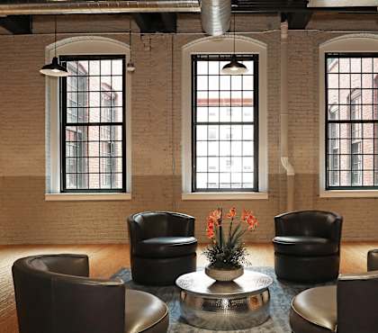 a lounge area with leather chairs and a table and windows