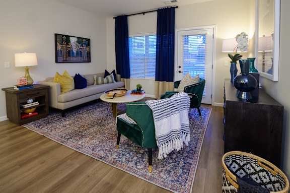 a living room with a couch a chair a table and a kitchen in the background