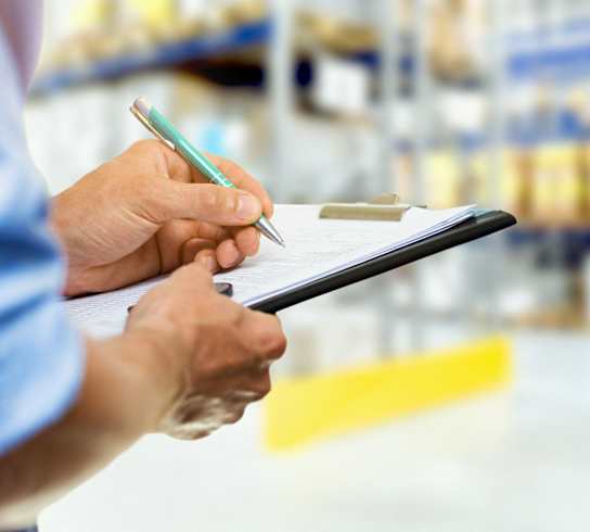 Person checking warehouse inventory on clipboard