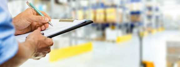 Person holding clipboard during warehouse inspection