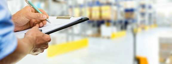 Person holding clipboard during warehouse inspection