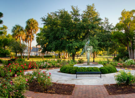 a fountain in the center of a park with flowers and trees