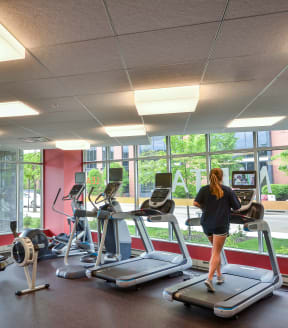 a woman on a treadmill in a gym with large windows