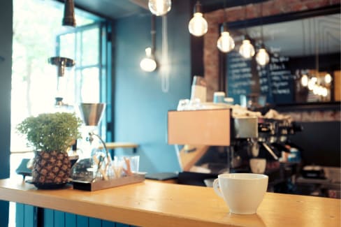 A white cup sits on a wooden counter in a cafe.