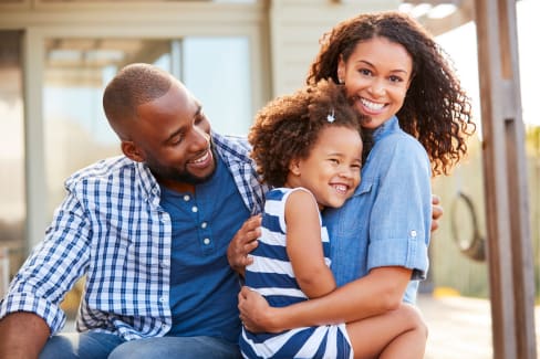 A family of three is sitting together outside.