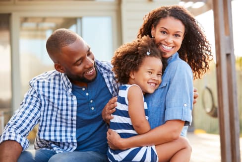 A family of three is sitting together outside.