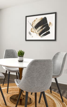 a dining room with a white table and chairs and a black and white painting