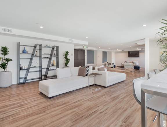 A white sofa set is placed in a room with wooden flooring at Wilshire Valencia Apartment, California