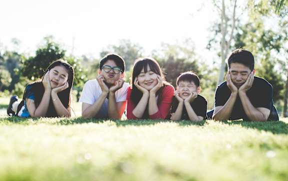 A family of four is sitting closely together on a couch.