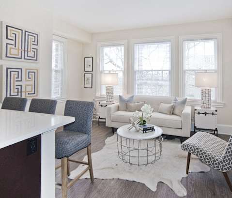 a living room with white couches and chairs and a white rug