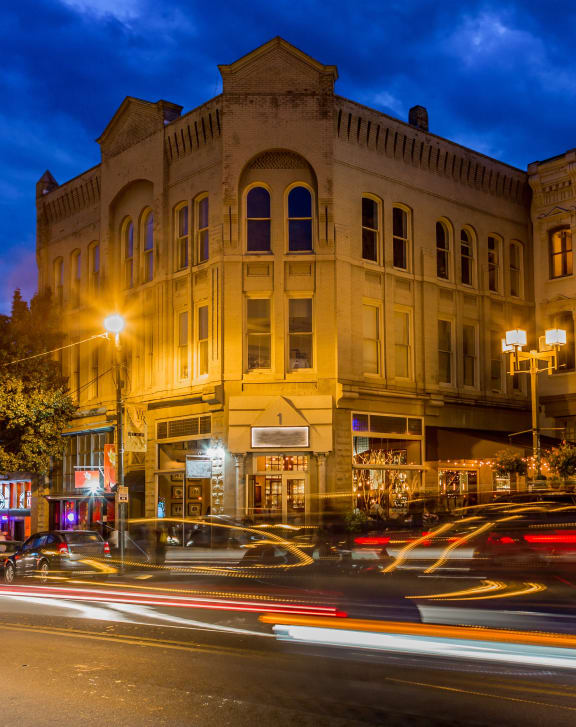 Downtown Asheville city street at night with cars and illuminated buildings.