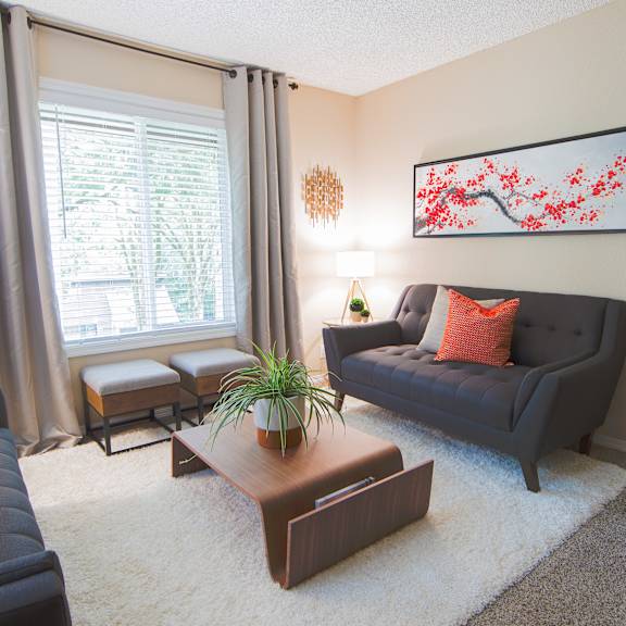 A living room with a black couch, a brown coffee table, and a red pillow.
