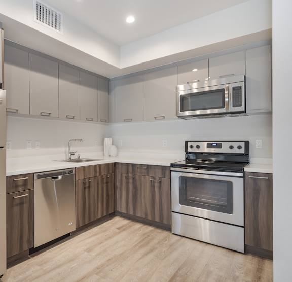 A modern kitchen with stainless steel appliances and wooden cabinets at Wilshire Valencia Apartment, California