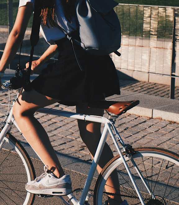 A woman is riding a bicycle on a paved path at The Bessemer at Seward Commons Apartments, MN, 55404