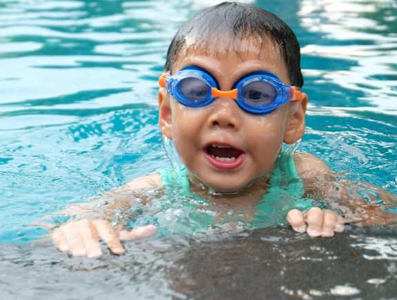 a young boy in a swimming pool wearing goggles