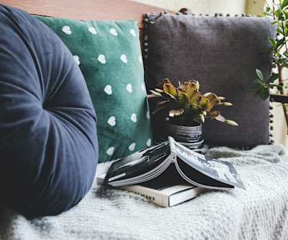 a bean bag chair with pillows and a book on a blanket