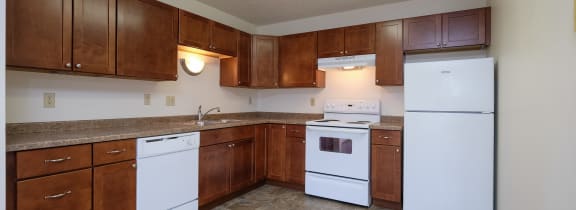 an empty kitchen with white appliances and wooden cabinets