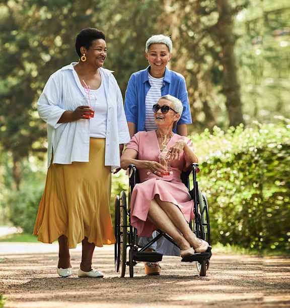 a woman in a wheelchair and two women walking in a park