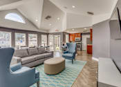 Thumbnail 2 of 4 - A living room with a grey sofa, a blue armchair, a white chair and a television.
