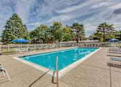Thumbnail 3 of 4 - A large outdoor swimming pool surrounded by trees and lounge chairs.