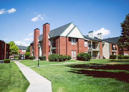 an apartment building with a green lawn and a sidewalk