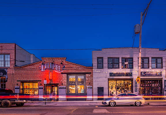 A car is driving past a building with a sign that says "Jim's".
