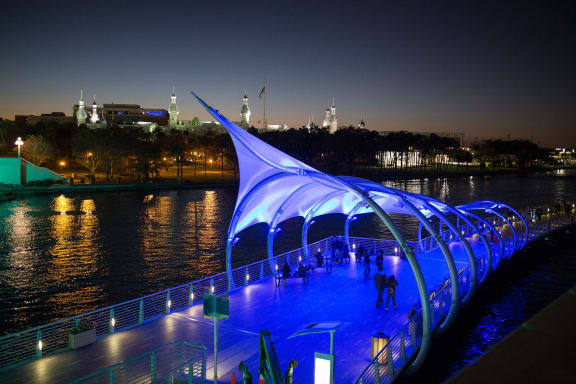 a blue lighted bridge over the water at night