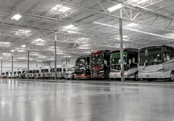 A large indoor storage space with airstreams, diesel pushers, and small and large vehicles.
