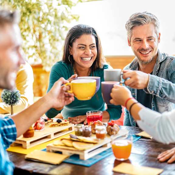 A group of people toasting with drinks at a table with food.