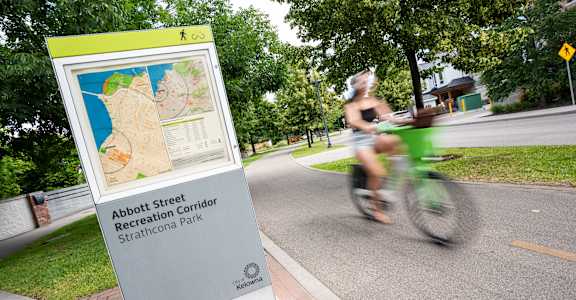A sign for Abbott Street Recreation Corridor Strathcona Park is on the sidewalk.