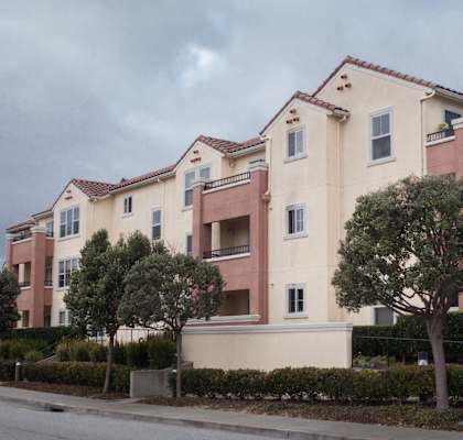 a row of pink and white apartments on the side of a street