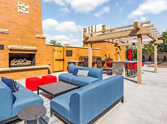 A patio with a blue couch and a fireplace.